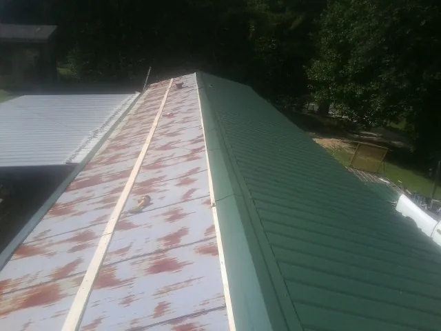 Old rusted panels beside newly installed green metal roofing — Wind Damage Roof Repair by Roofing Brothers in Waconia