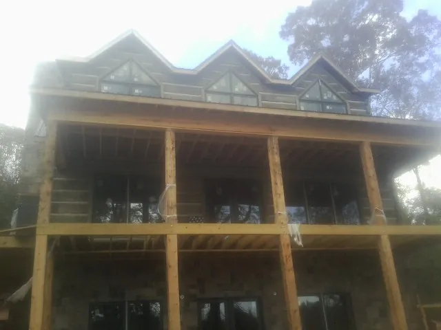 Dormers and porch framing on a large log home under construction — Roof Coating work by our crew in Waconia