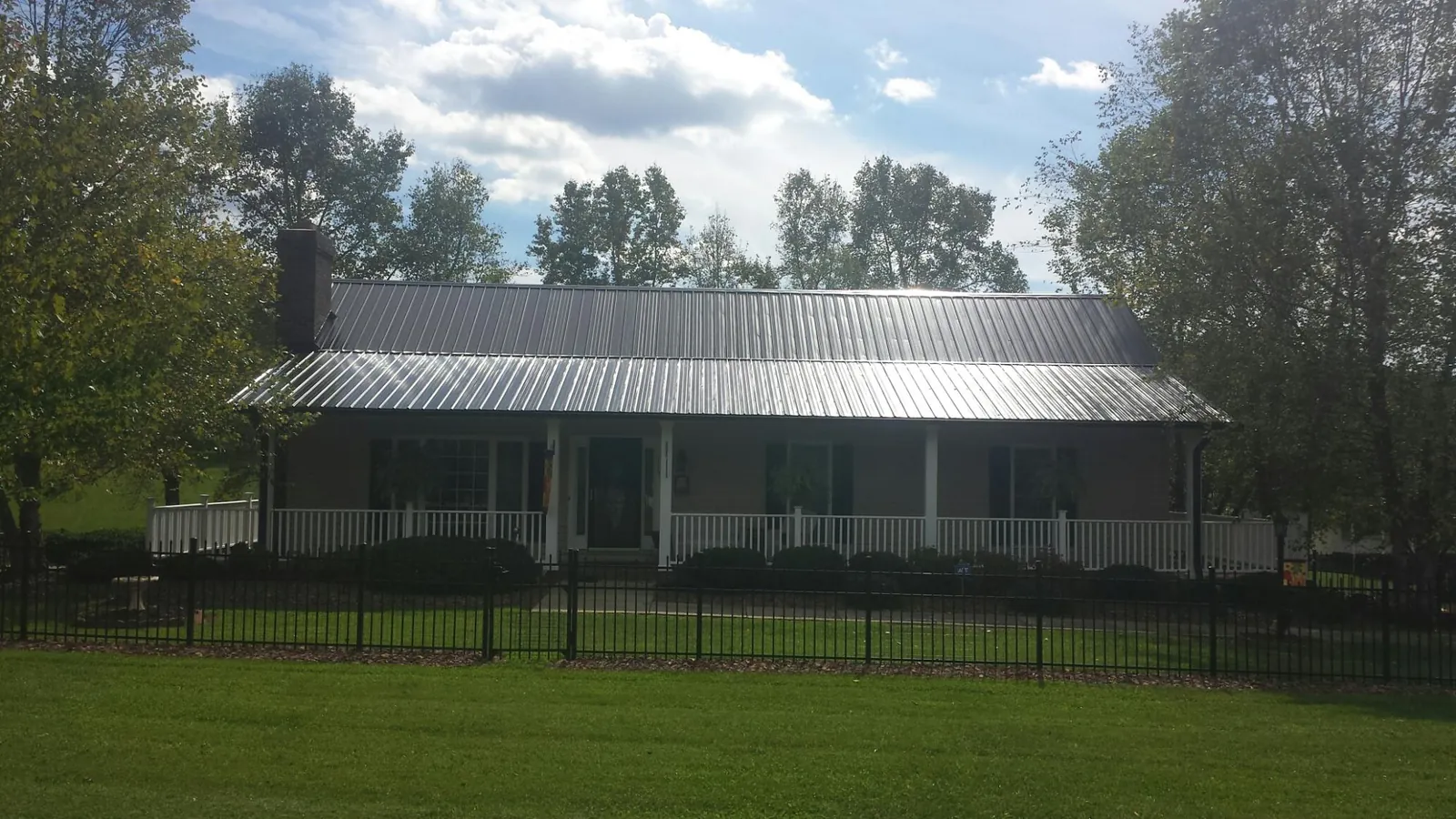Gray metal roof on a brick ranch with a full width front porch — Gutter Guard Installation work by our crew in Waconia