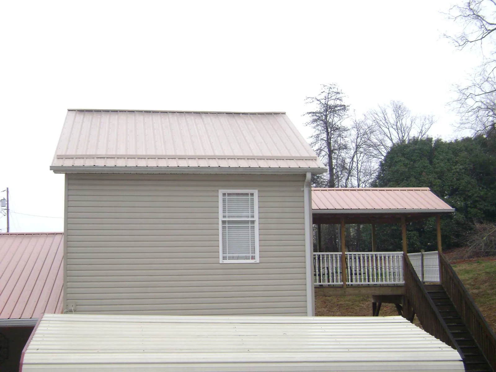 Tan metal roofs on a two story addition and attached porch, from a Roof Replacement job in Waconia