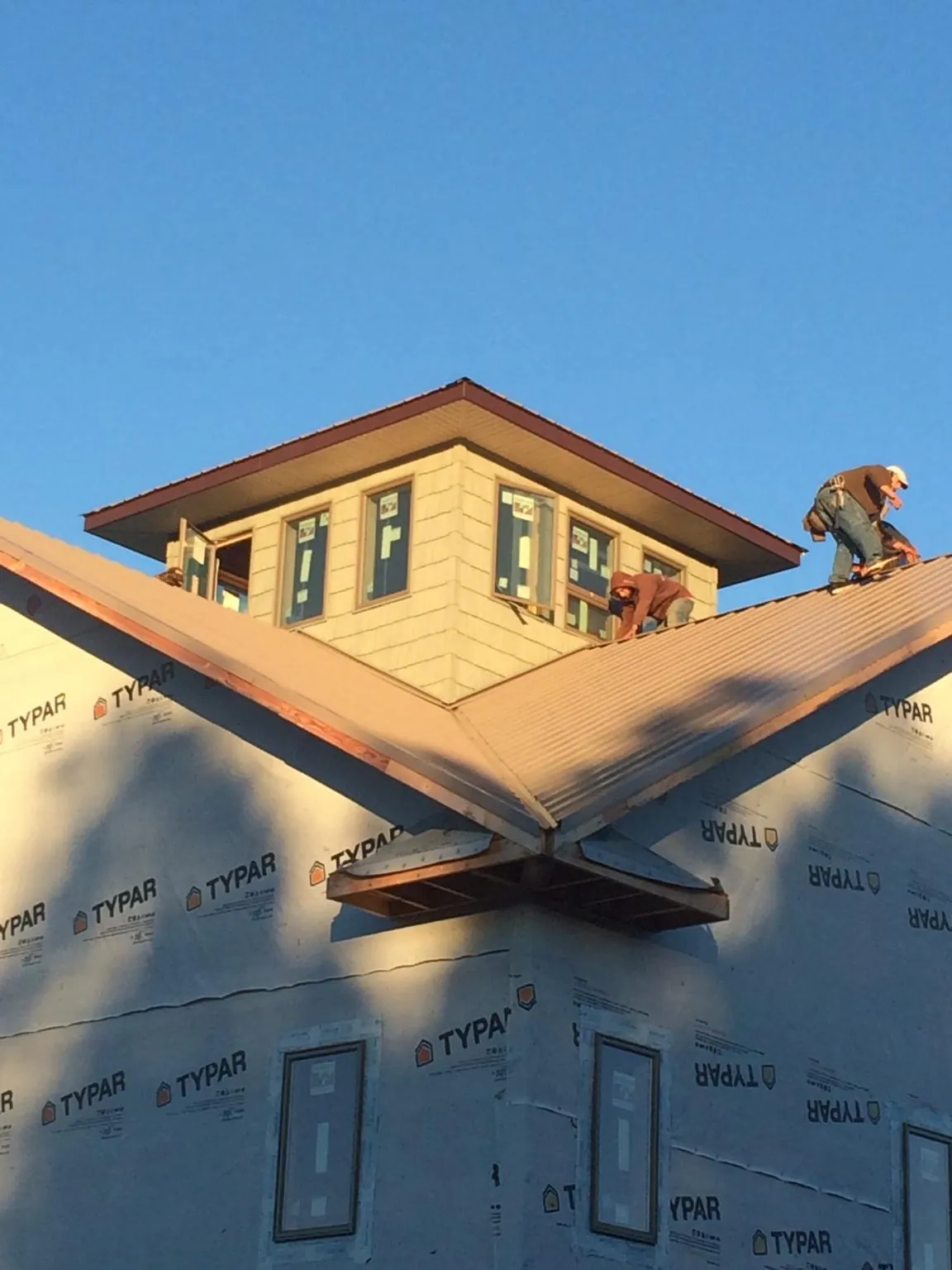 Roofers working around a rooftop cupola on a new metal roof at sunset — Roof Waterproofing in Waconia by Roofing Brothers